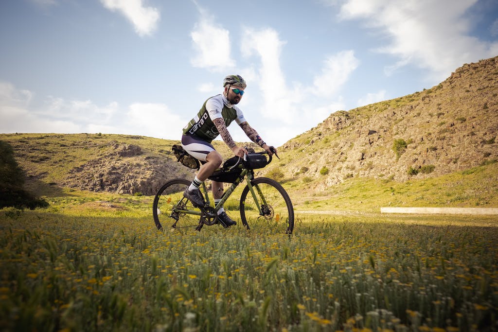 Man in Black and White Shirt Riding Black Mountain Bike on Green Grass Field